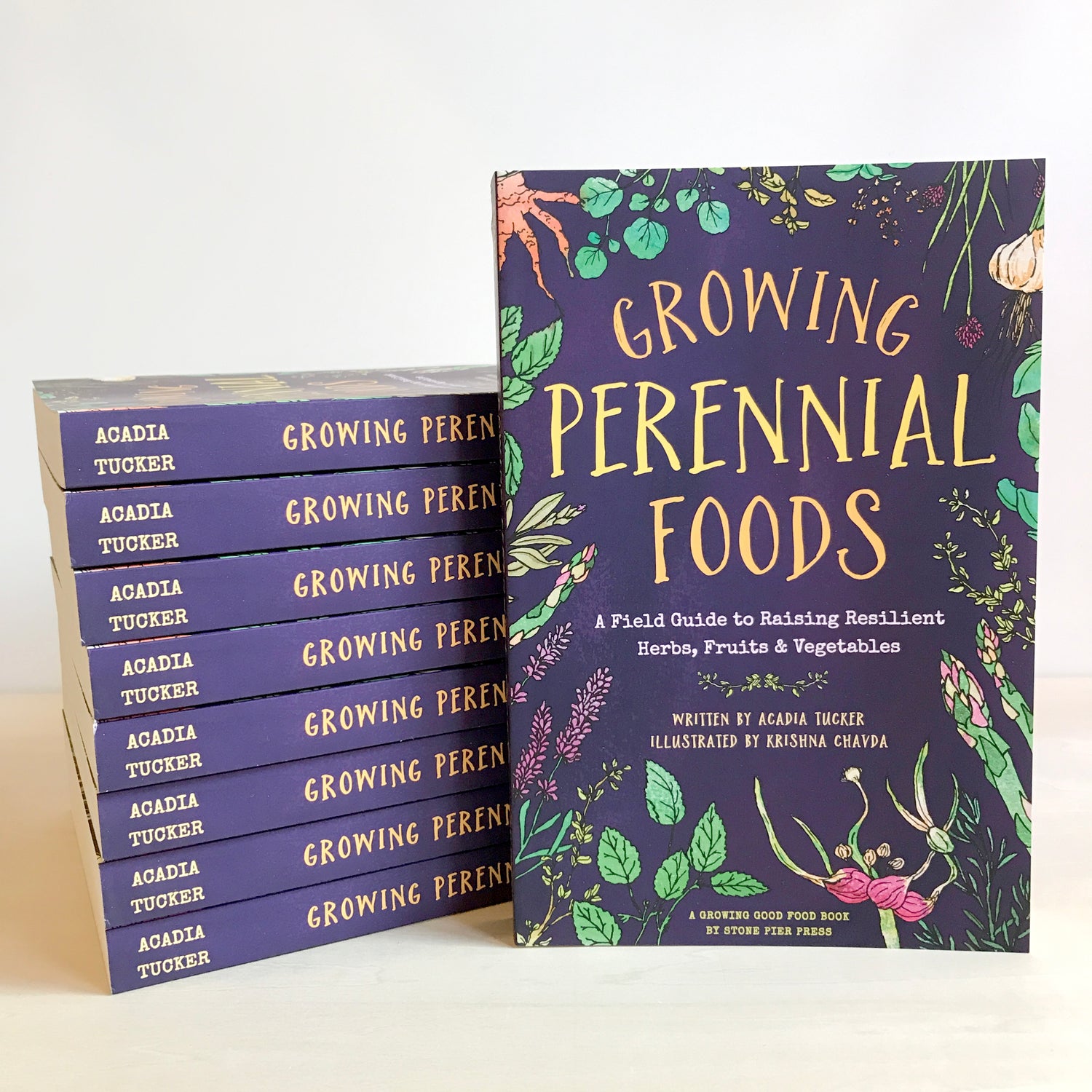 "growing perennial foods" book showcasing front cover while standing up against a stack of the same books