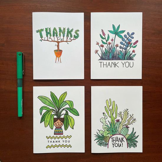 Four plant-themed thank you cards in a grid on a wood surface with a green pen to the left. 